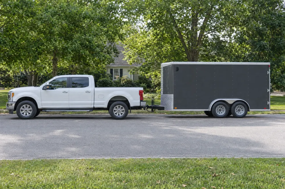White work pickup towing an enclosed landscape equipment trailer